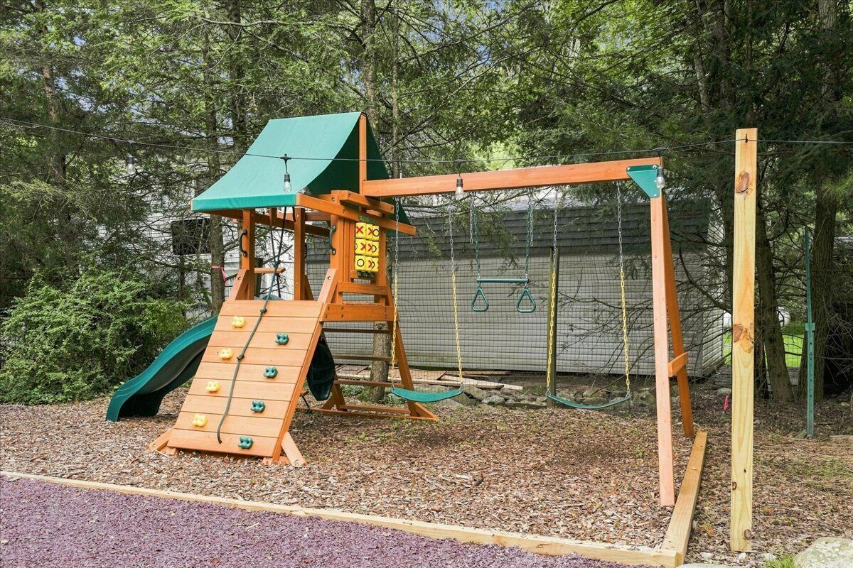 A playground with a slide, climbing wall, and swings.