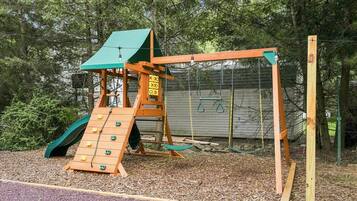 A playground with a slide, climbing wall, and swings.