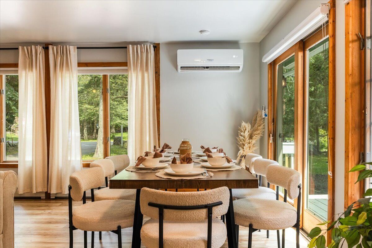 A dining room with a wooden table set for six, surrounded by upholstered chairs.