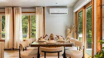 A dining room with a wooden table set for six, surrounded by upholstered chairs.