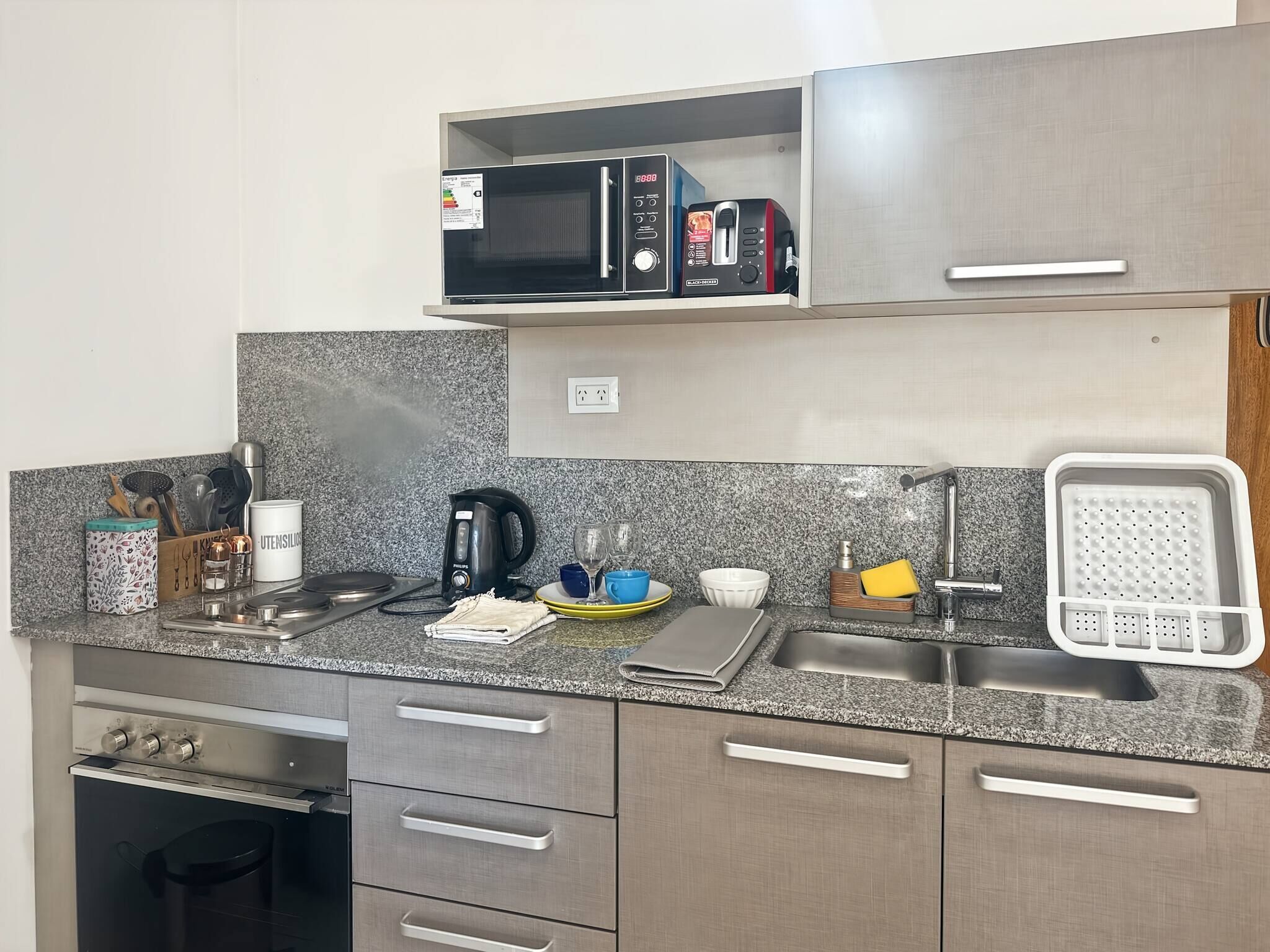 Cozinha equipada com micro-ondas, torradeira, chaleira, pia e diversos utensílios.