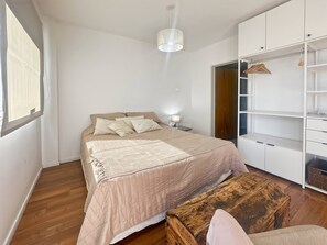 A bedroom with a bed, bedside table, wardrobe, and a wooden bench. - Charming Central Buenos Aires Apartment With City Views (Buenos Aires)