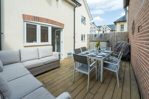 A patio with a dining table set for four, a sofa, and a covered barbecue grill. - Stylish, Spacious Townhouse in the Heart of Ludlow - Pass the Keys (Ludlow)