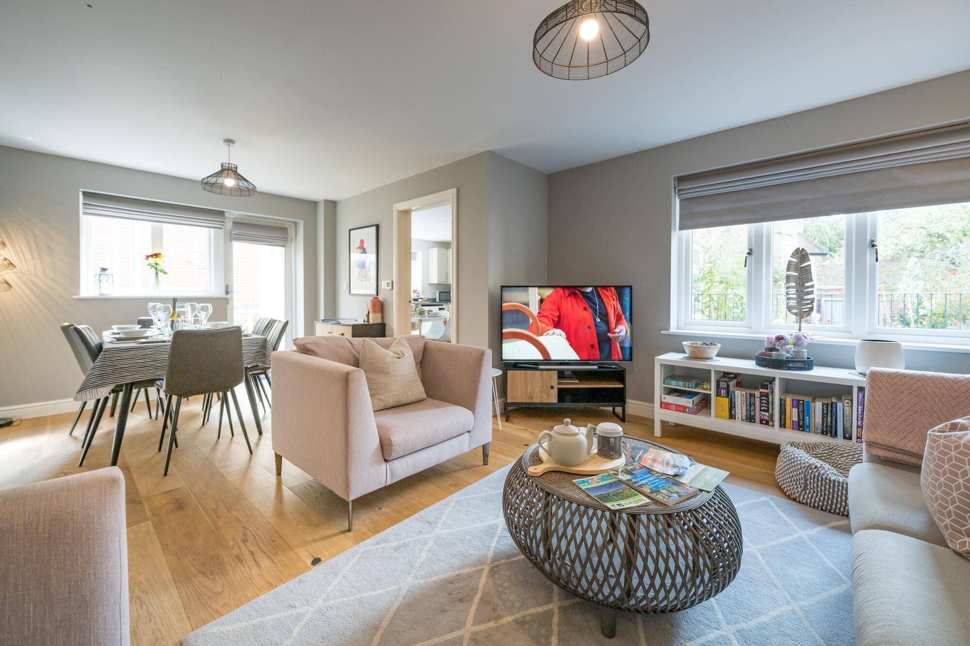 Uma sala de estar moderna com sofá, mesa de centro, televisão e estante de livros.