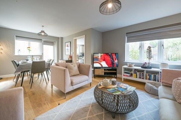 A modern living room with a sofa, coffee table, TV, and bookshelf. - Stylish, Spacious Townhouse in the Heart of Ludlow - Pass the Keys (Ludlow)