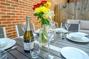 A dining table set with a bottle of wine, glasses, and a vase of flowers. - Stylish, Spacious Townhouse in the Heart of Ludlow - Pass the Keys (Ludlow)