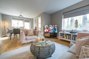 Ein Wohnzimmer mit Sofa, Couchtisch, Fernseher und Bücherregal.