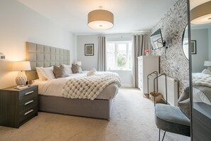 A modern bedroom with a large bed, bedside tables, a dresser, a chair, a radiator, and a window with curtains. - Stylish, Spacious Townhouse in the Heart of Ludlow - Pass the Keys (Ludlow)