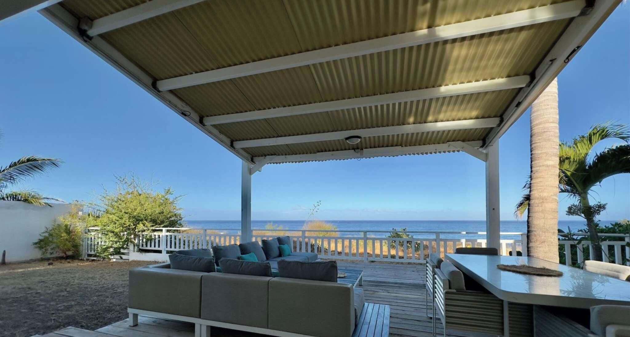 A covered outdoor seating area with a view of the ocean.