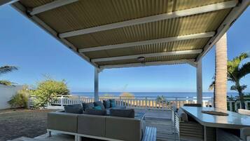 A covered outdoor seating area with a view of the ocean.