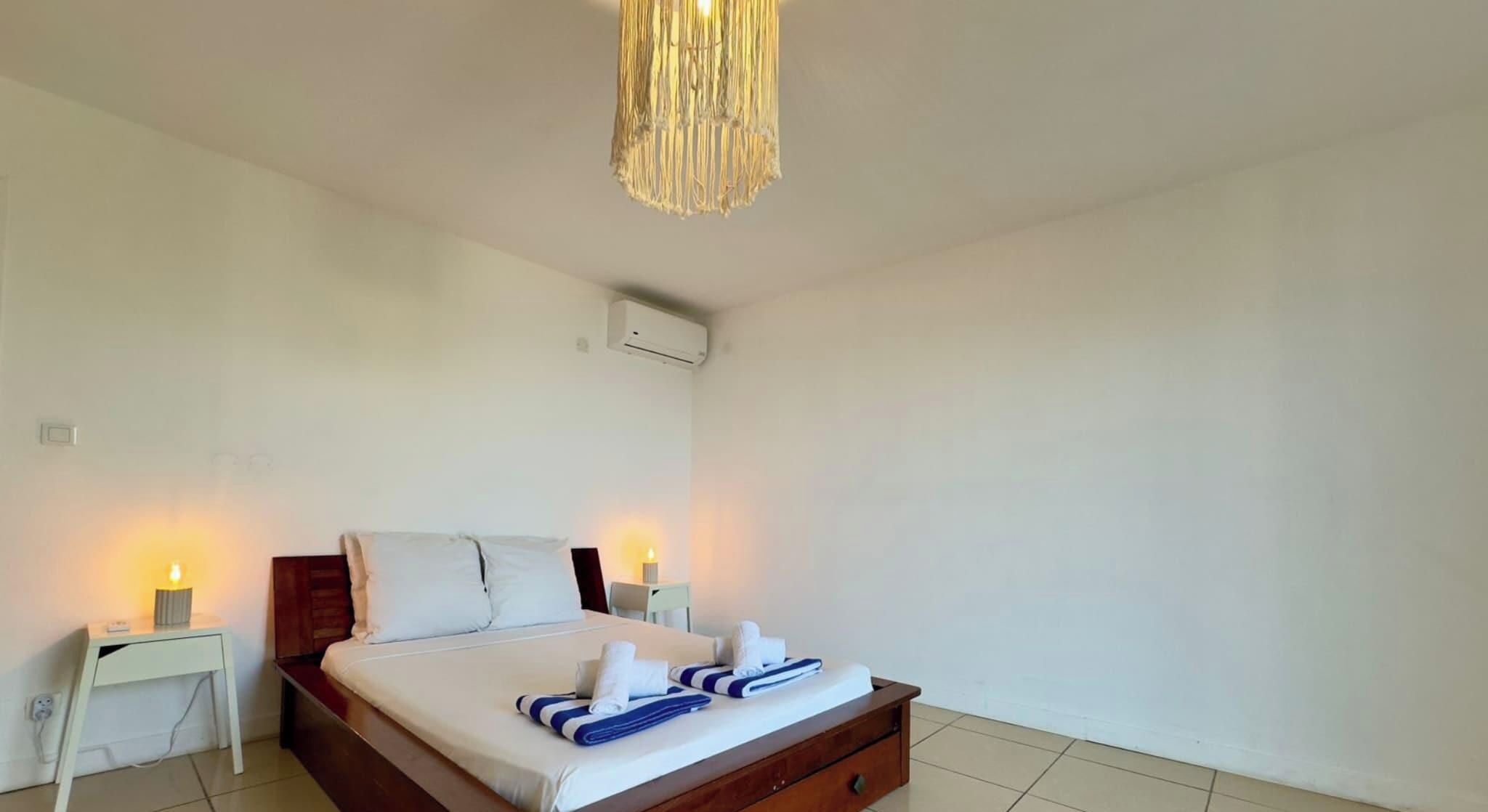 Une chambre d’hôtel avec un lit, des tables de chevet et un luminaire suspendu.