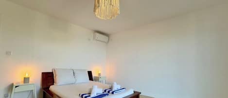 Une chambre d’hôtel avec un lit, des tables de chevet et un luminaire suspendu.