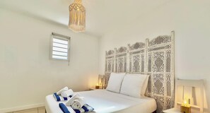 Habitació d'hotel amb un llit, un panell decoratiu al capçal, una finestra petita i una làmpada de nit.