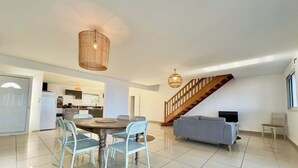 Un vaste espace de vie comprenant une table à manger, des chaises, un canapé et un escalier.