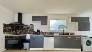 Une cuisine moderne équipée d’une cuisinière, d’un lave-vaisselle et d’un lave-linge.