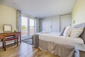 A bedroom with a bed, a desk, and a view through a glass door. - Charming House with Pretty Garden & Parking - Pass the Keys (Chichester)