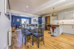 A modern kitchen with white cabinets, a wooden countertop, and a red bar stool. - Charming House with Pretty Garden & Parking - Pass the Keys (Chichester)