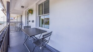 A balcony with a table and chairs, a hanging plant, and a view of the sea. - Lovely 2 Bedroom Coastal Flat - Pass the Keys (Bognor Regis)