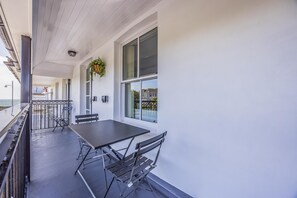 Een balkon met een tafel en stoelen, een hangplant en uitzicht op zee.