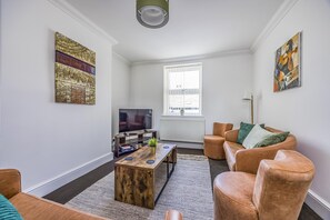 Een woonkamer met een televisie, een houten salontafel, leren banken en kunstwerken aan de wanden.