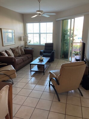 Una sala de estar con sofá, sillón, mesa de centro y ventilador de techo.