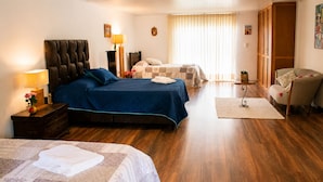 Habitación de hotel con dos camas, zona de estar y vistas al exterior.