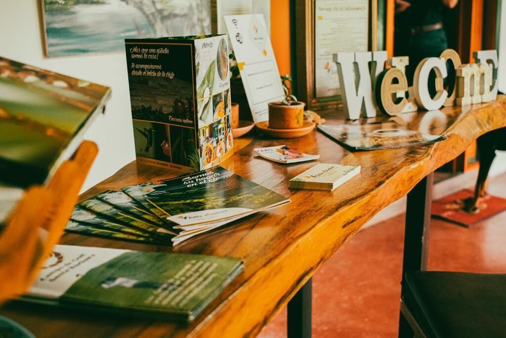 Una mesa de recepción con folletos, un cartel de bienvenida y una taza de café.