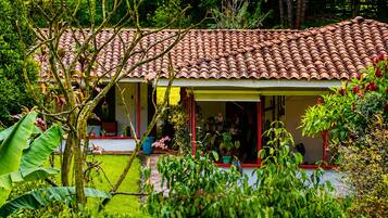 Una casa con techo de tejas, rodeada de abundante vegetación y plantas.