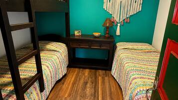 Una habitación con dos literas, un escritorio, un tapiz de macramé y suelo de madera.