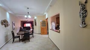A dining area with a table and chairs, a kitchen area with cabinets, and a zebra wall decoration. - Spacious Downtown Boquete 2BR/2BA Condo with Private Balcony (Bajo Boquete)