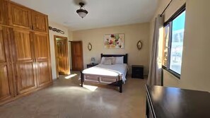 A bedroom with a bed, wardrobe, and a window. - Spacious Downtown Boquete 2BR/2BA Condo with Private Balcony (Bajo Boquete)