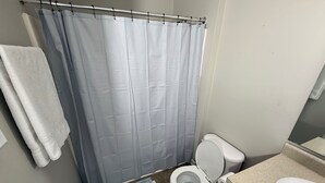 Ein Badezimmer mit Duschvorhang, Toilette, Waschbecken und Handtuchhalter.