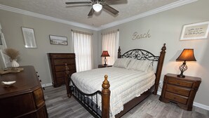 Ein Schlafzimmer mit Bett, Kommode, Nachttischen und einem Deckenventilator.