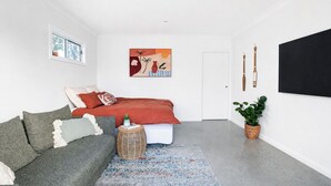 A modern bedroom with a bed, a sofa, a rug, and a potted plant. - Stones Throw - Located right in the heart of Robe (Robe)