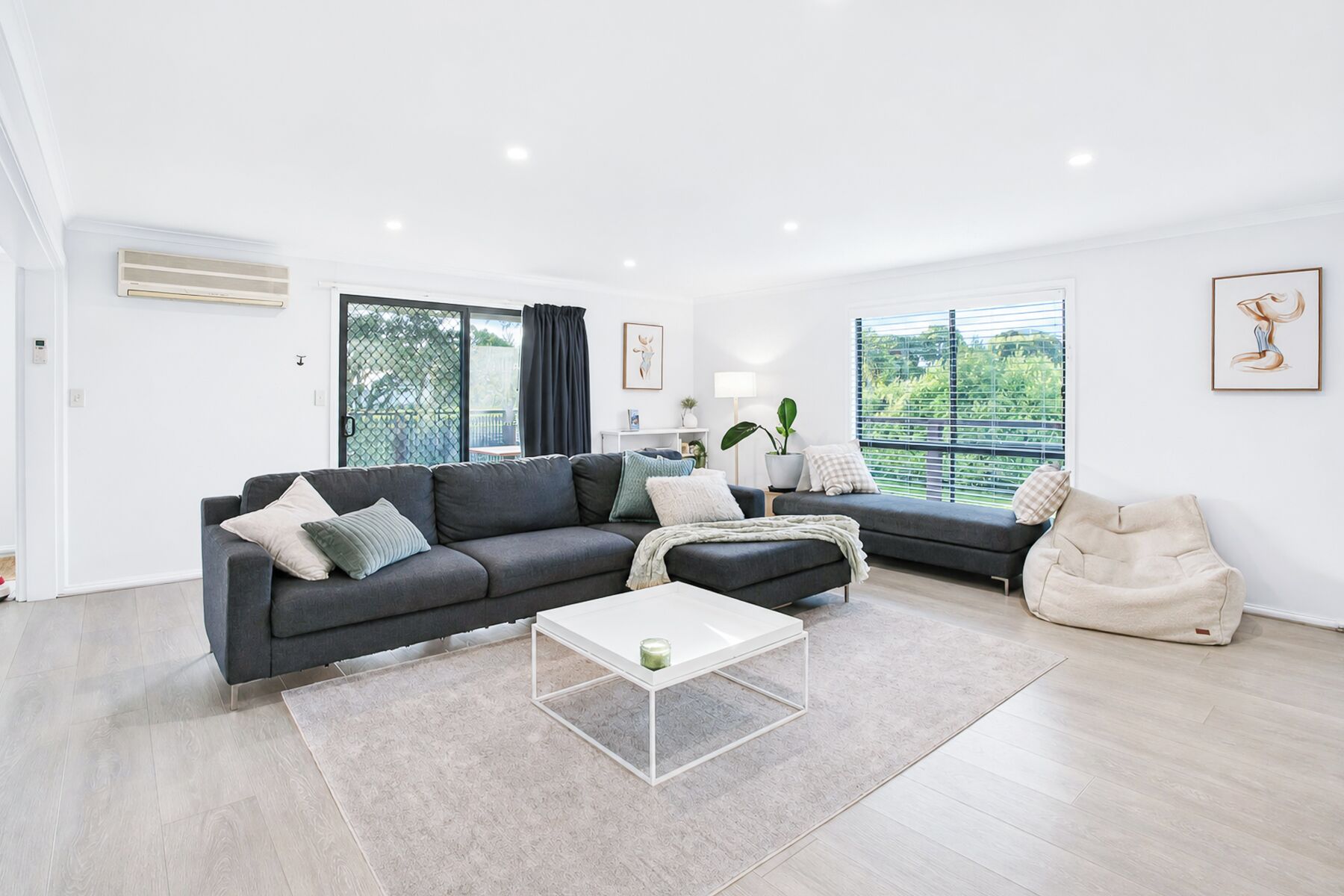 Una sala de estar moderna con un sofá seccional, una mesa de centro blanca y un sillón beige.