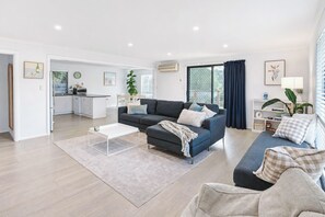 A modern living room with a grey sofa, a coffee table, and a dining area in the background. - Stones Throw - Located right in the heart of Robe (Robe)
