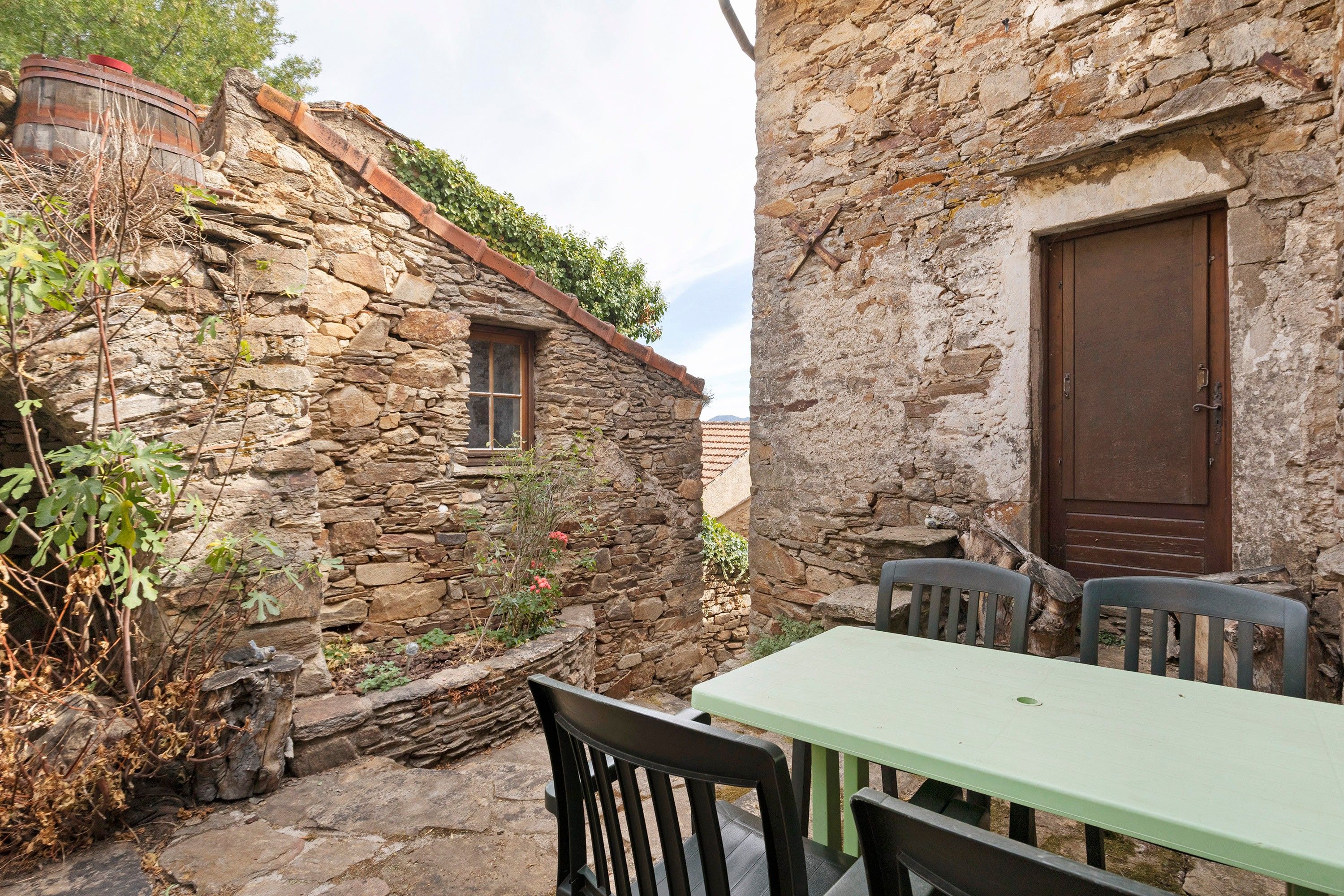 A stone building with a door, a window, and a table with chairs.