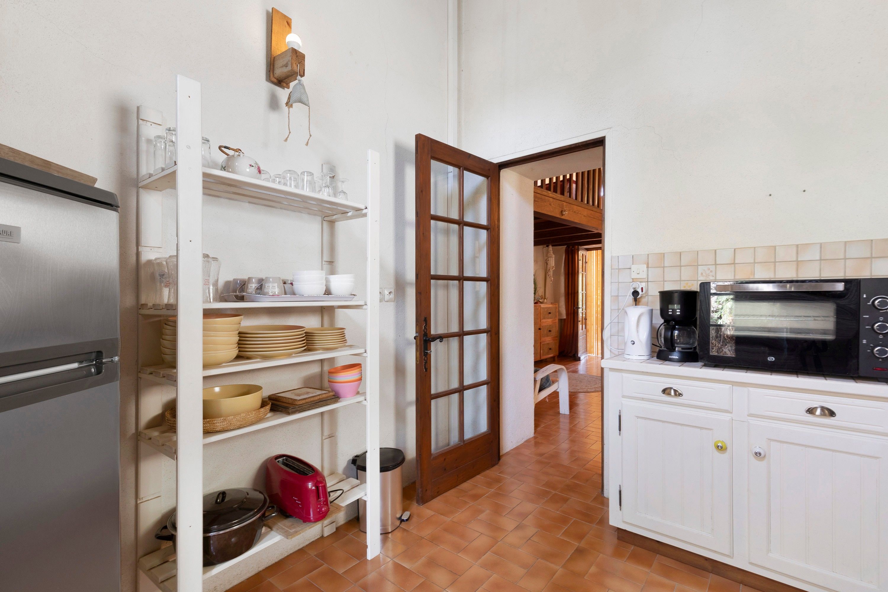 A kitchen with white cabinets, a built-in oven, a coffee maker, and a toaster.