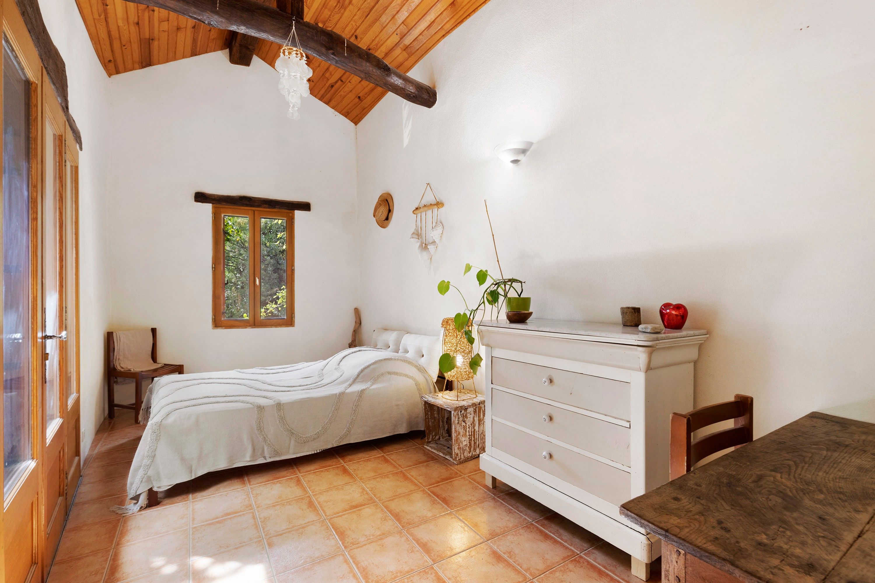 Quarto com cama, penteadeira, janela e planta.