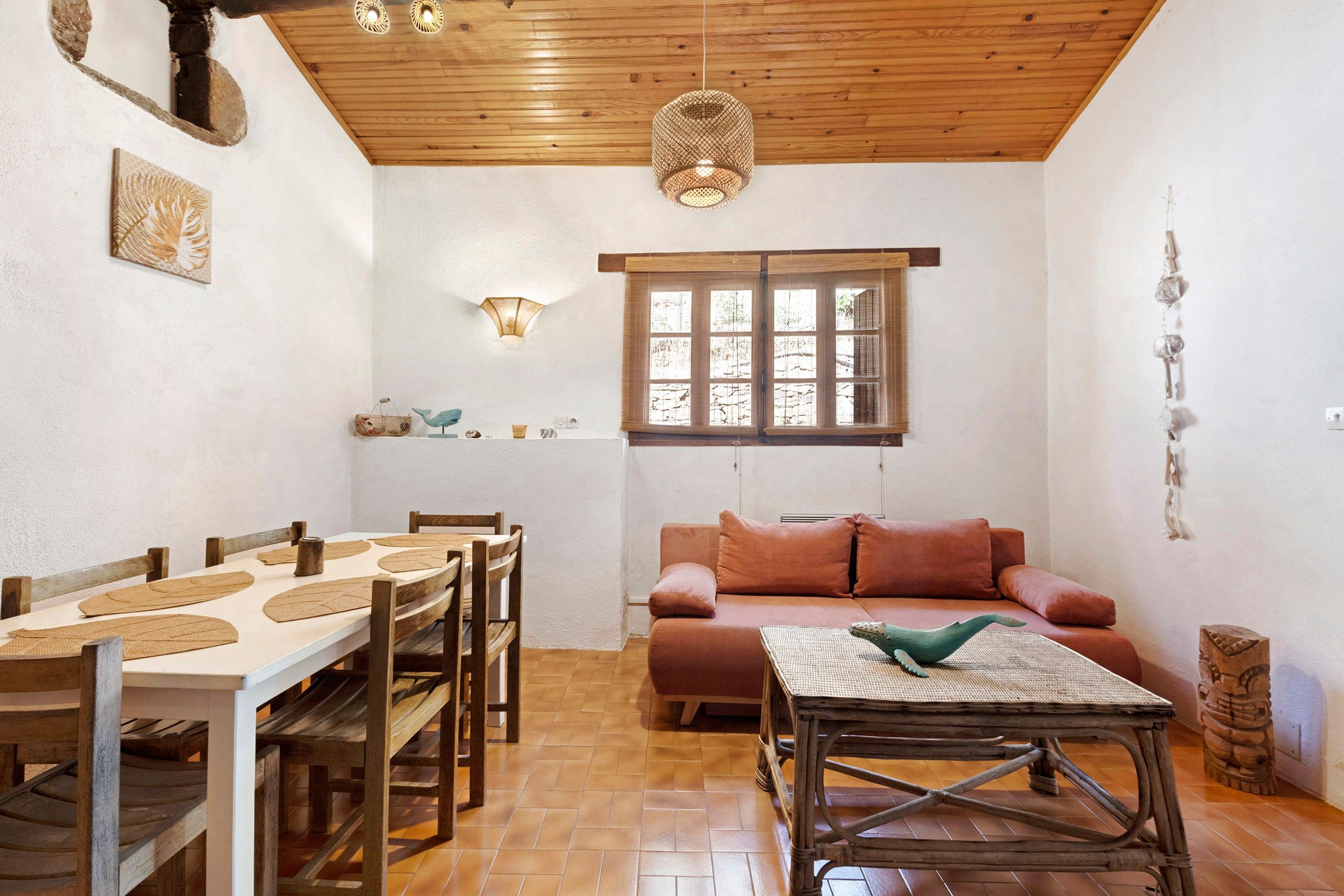 A cozy interior with a dining area, a sofa, and a window with blinds.