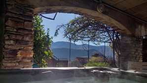 Un bain à remous avec vue sur les montagnes et un mur en pierre.