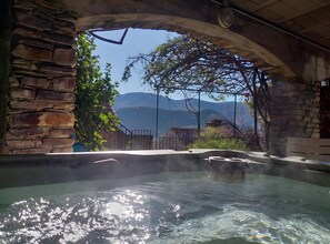A hot tub with a view of mountains and a stone wall. - Holiday Home 'Gîte La Belle Étoile' with Mountain View and Private Terrace (Saint-Julien)