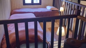 Une chambre avec un plafond en bois, une fenêtre, un lit avec des oreillers et une table de chevet avec une lampe.