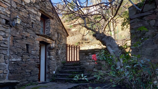 Un bâtiment en pierre avec une porte en bois et des marches menant à un niveau supérieur.