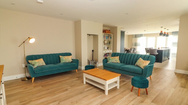 A spacious living room with two teal sofas, a wooden coffee table, and a floor lamp. - Ceol Na Mara (Creegh)