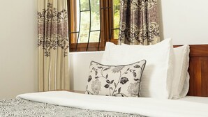 Ein Schlafzimmer mit einem Bett, einem Fenster mit Vorhängen und einer Wandleuchte.