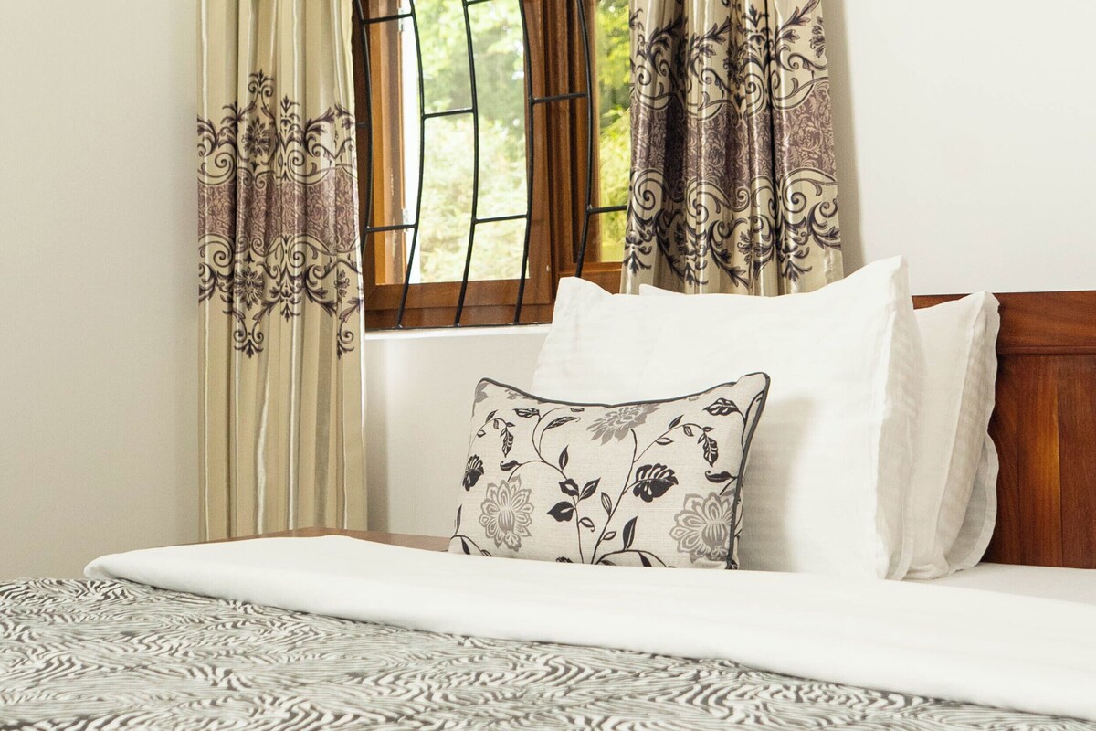 Een slaapkamer met een bed, een raam met gordijnen en een wandlamp.