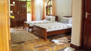A room with two wooden beds, a stone floor, and a door with a brass handle.