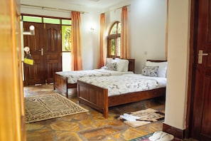 Una habitación con dos camas de madera, suelo de piedra y una puerta con tirador de latón.