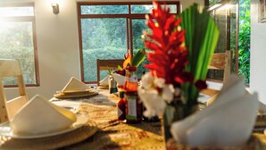 Ein Esstisch, gedeckt mit Tellern, einer Flasche und einer Blumenvase.